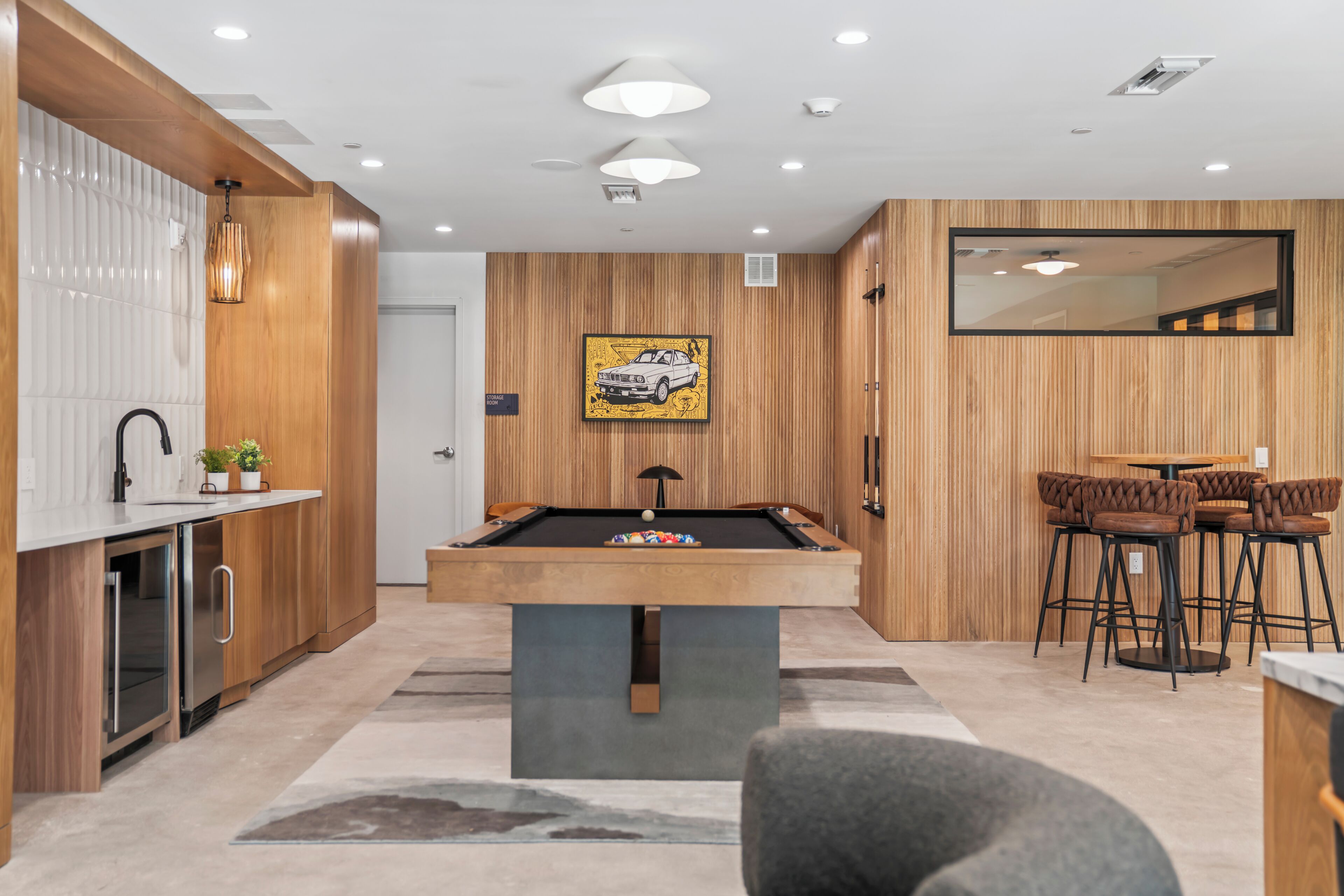 Une cuisine moderne avec un billard, des lambris en bois et un coin repas équipé de tabourets de bar.