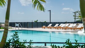 A swimming pool with lounge chairs and a fence.