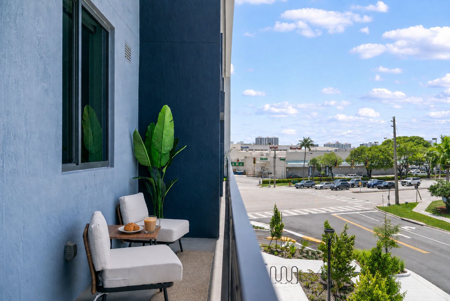 A balcony with a seating area, a large window, and a view of a city street.
