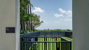 A view of a fenced outdoor area with a grassy field, a red fire hydrant, and a bench.