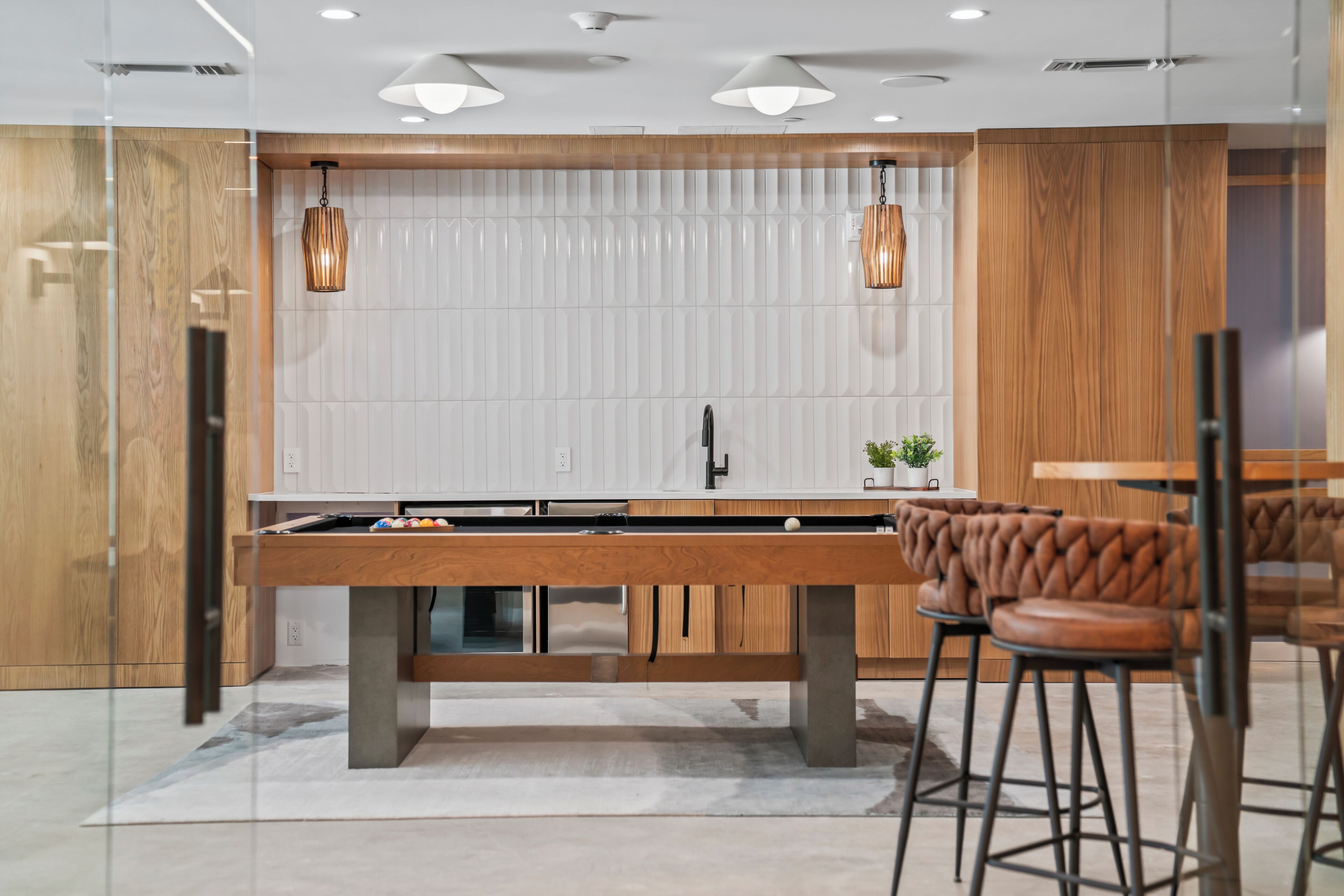 A modern kitchen with a central island, pendant lighting, and wooden cabinetry.