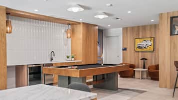 A modern living room with a pool table, wooden accents, and a dining area.