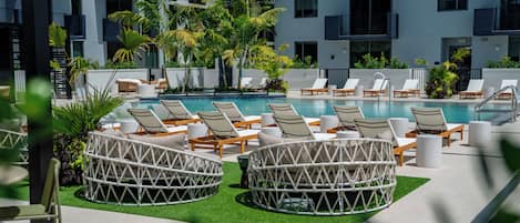 Un área de piscina con sillones de descanso y un pequeño jardín.