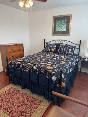 A bedroom with a bed, a wooden dresser, a patterned rug, a framed picture on the wall, and a ceiling light fixture. - Experience Baltimore’s charm city charm neighborhood by John Hopkins Bayview (Baltimore)