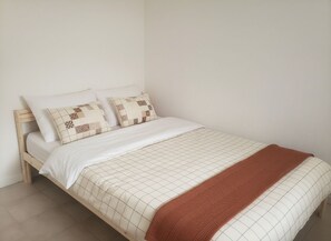 A bed with a quilted bedspread and two pillows, a wooden headboard, and a brown throw blanket. - Your ground floor apartment in Rouen. Downtown, 5 minutes from Place du Vieux Marché. (Rouen)