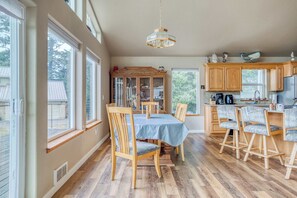 Una cocina amplia con armarios de madera, una mesa de comedor con sillas y un ventanal que proporciona luz natural.