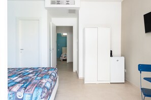 Een slaapkamer met een bed, een kledingkast, een bureau en een televisie.