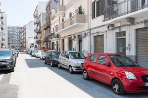 Een rij geparkeerde auto's langs een straat met meerhoogbouw, waarvan sommige balkons en airconditioners hebben.