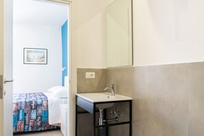 A hotel room with a bed, a bathroom with a sink and mirror, and a wall-mounted picture. - Alba Chiara Guest House - Sea View by BarbarHouse (Bari)
