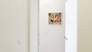 Una porta blanca amb un quadre colorit al mur de sobre.