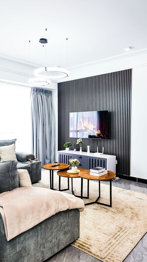 A modern living room with a sofa, coffee table, and a flat-screen TV mounted on a wall. - 2-bedroom apartment in beautiful Nairobi with fitness room access (Nairobi)