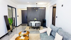 A modern living room with a round dining table, grey sofa, and a coffee table with books and a vase. - 2-bedroom apartment in beautiful Nairobi with fitness room access (Nairobi)