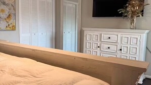 A bedroom with a bed, a ceiling fan, a dresser, and a television on the wall. - Wellington Polo Tranquility (Wellington)