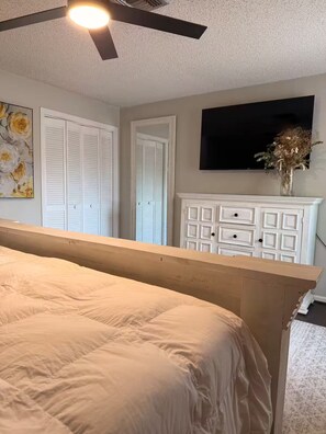 A bedroom with a bed, a ceiling fan, a dresser, and a television on the wall. - Wellington Polo Tranquility (Wellington)