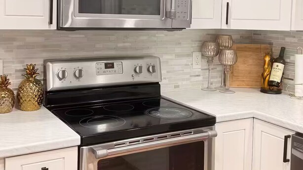 A kitchen with white cabinets, a stainless steel stove, and a microwave. - Wellington Polo Tranquility (Wellington)