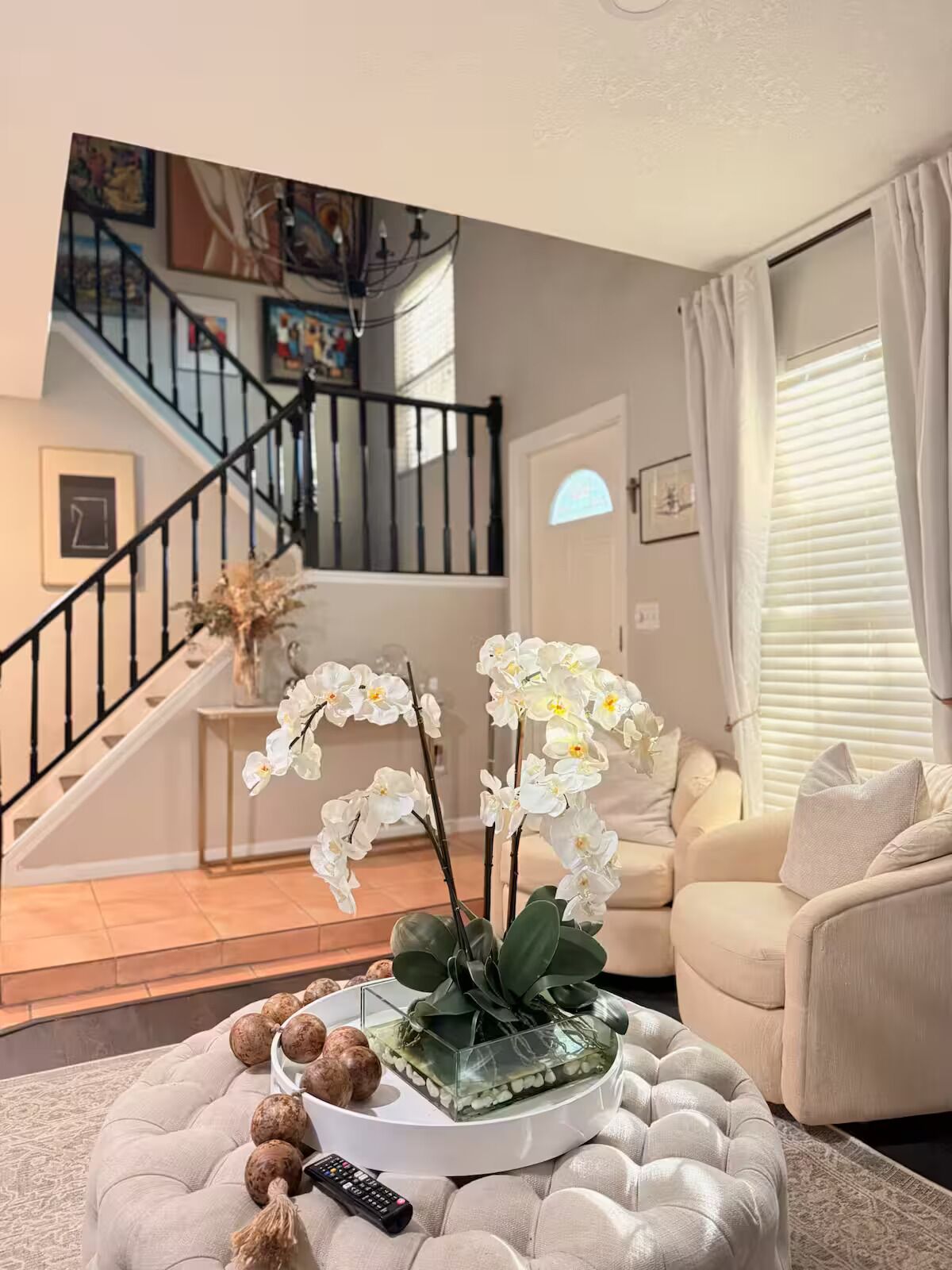 A living room with a sofa, a coffee table with decorative items, a staircase, and artwork on the walls.