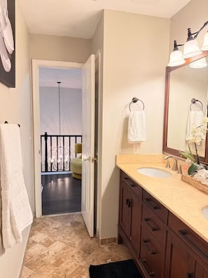 A bathroom with a double sink, a large mirror, and a view of a balcony.