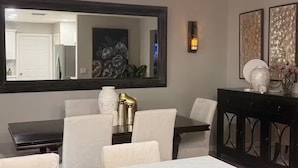 A modern kitchen with a marble countertop, a dining area with a large mirror, and a dark wooden cabinet. - Wellington Polo Tranquility (Wellington)