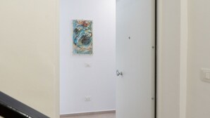 Un pasillo con una puerta blanca, un interruptor de luz y un enchufe en la pared.