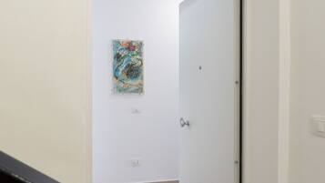 Un pasillo con una puerta blanca, un interruptor de luz y un enchufe en la pared.