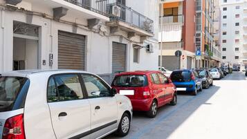 Una fila de coches estacionados a lo largo de una calle urbana, con edificios a ambos lados.