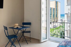 Ein Balkon mit Tisch und Stühlen, Blick auf das Meer, und ein Gebäude mit Gerüst.