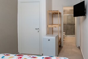 A narrow hallway with a white door, a small white refrigerator, a wooden shelf unit, and a toilet visible through a glass partition. - Alba Chiara Guest House - City View by BarbarHouse (Bari)