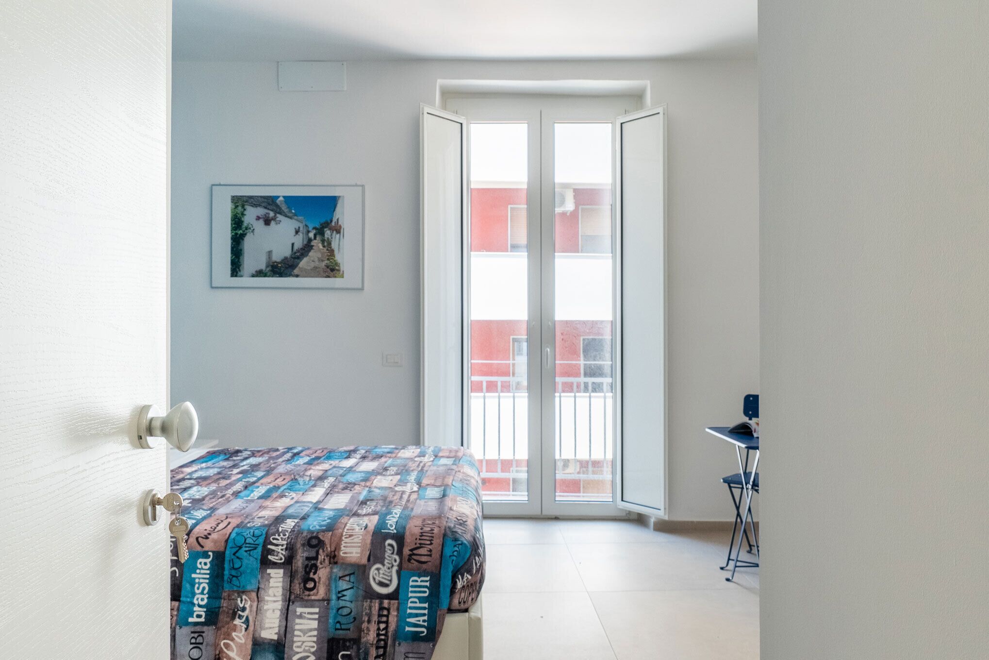 Une pièce avec un lit, une porte, une fenêtre et une chaise.