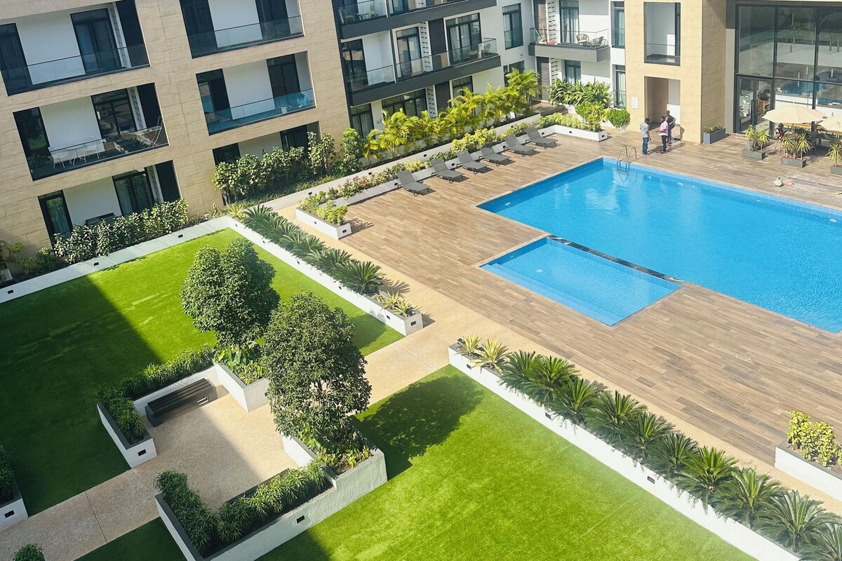 Un edificio moderno con piscina, varios balcones y un césped bien cuidado.