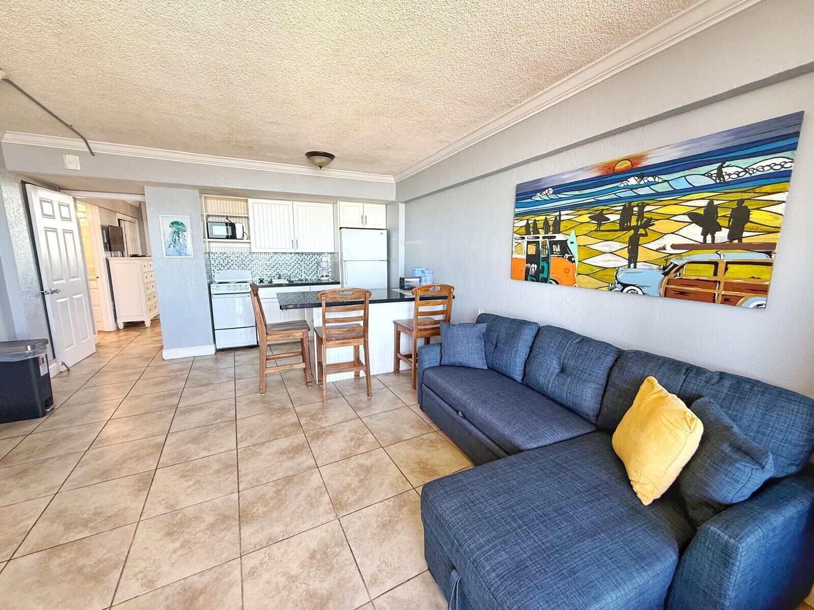 A compact living space with a kitchenette, a dining area, and a sofa with a cushion.