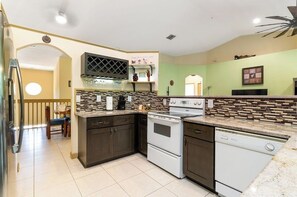 Uma cozinha com armários escuros, um fogão branco e uma lava-louças.