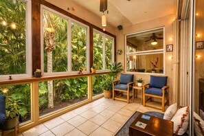 A room with large windows, wooden furniture, and a view of lush greenery. - Executive 3BR • Pet‑Friendly • Fully Furnished • Near I‑95 & Tpke • 21‑Night Min (Delray Beach)