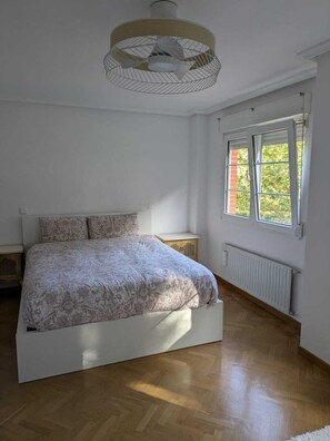 Un dormitorio con cama, ventana y ventilador de techo.