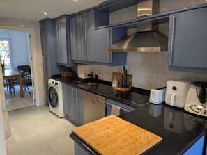 Una cocina moderna con electrodomésticos de acero inoxidable, una tabla de cortar de madera y un comedor con mesa y sillas.