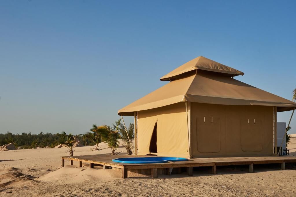 A desert tent with a wooden deck and a blue pool.