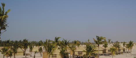 Un resort con varias cabañas, palmeras y una playa de arena.
