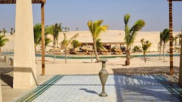 Ett semesterparadis vid stranden med palmer, en pool och en lusthusliknande byggnad.