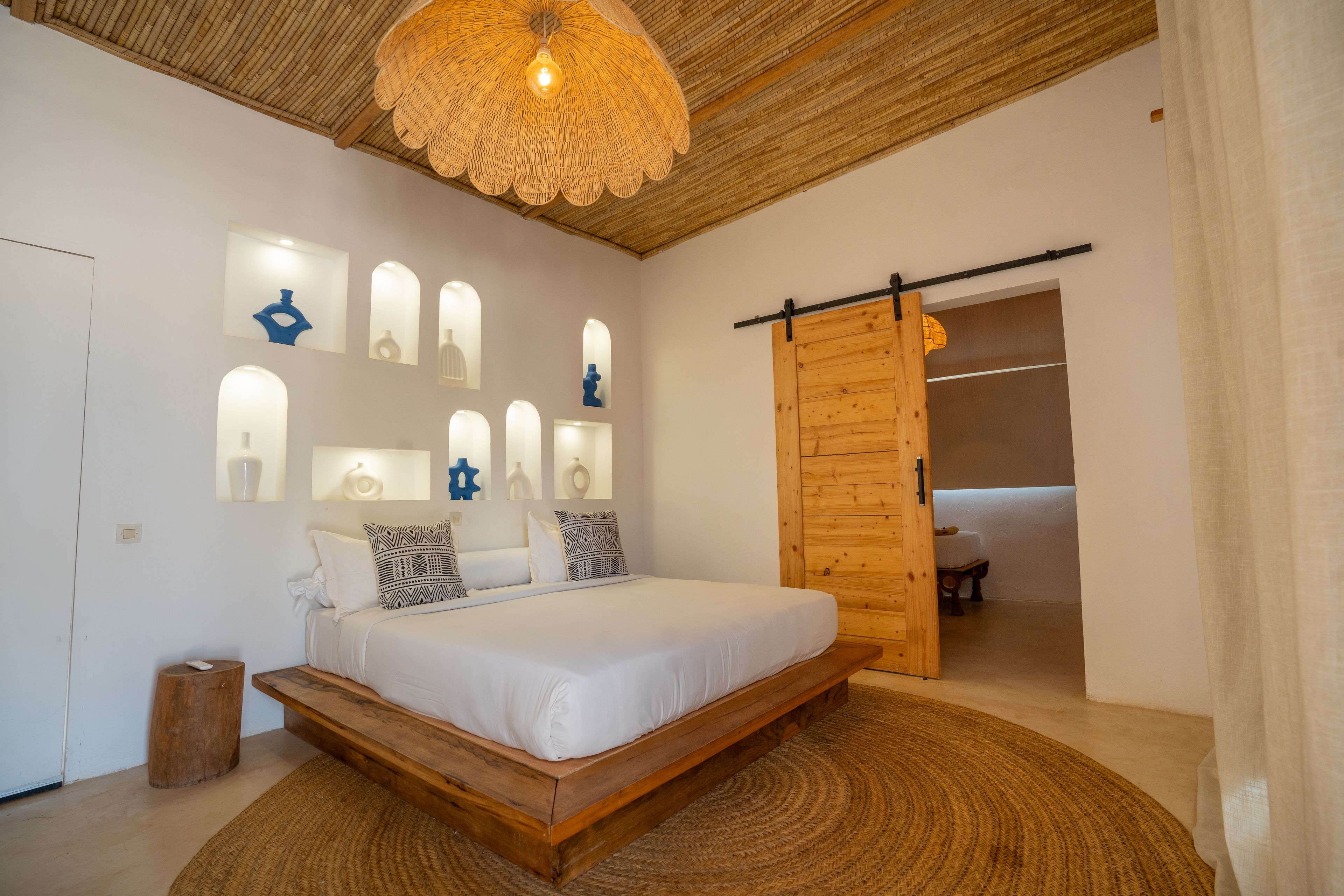 A bedroom with a wooden bed, a woven rug, and a ceiling fan.