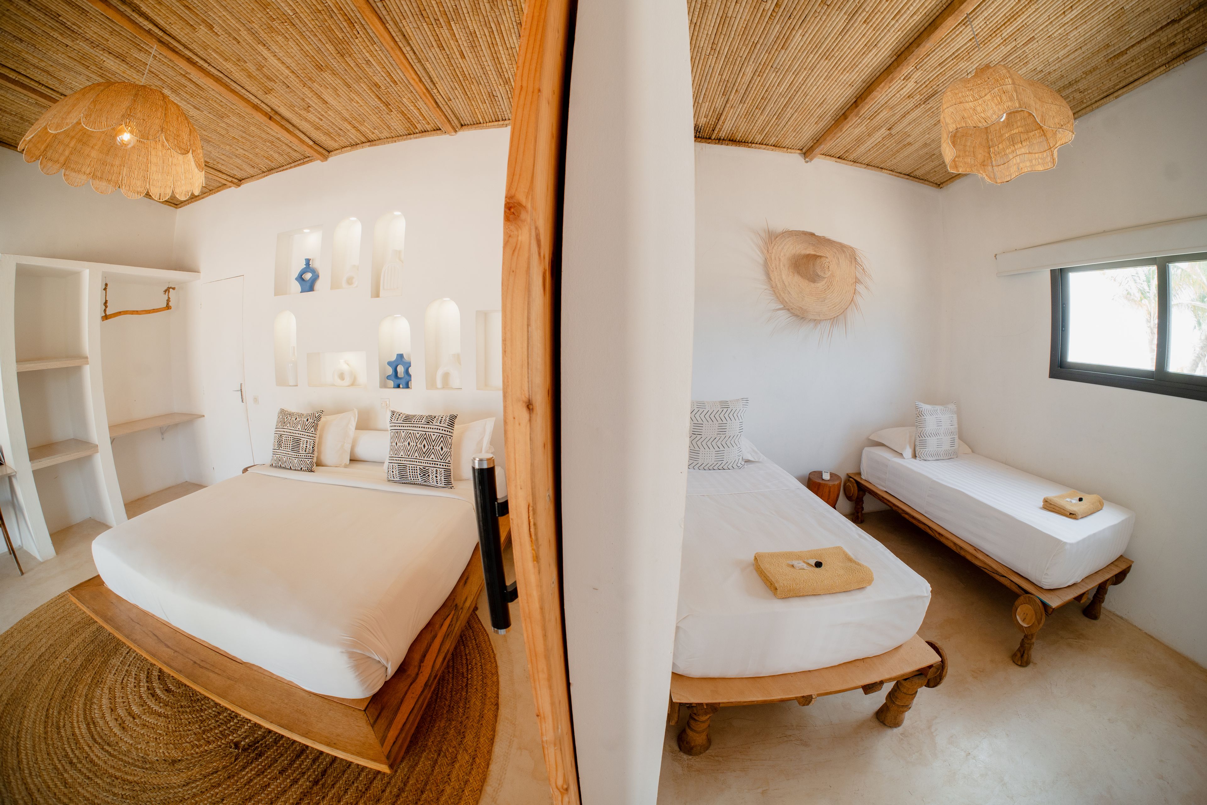 Een kamer met een groot bed, een kleiner bed, een raam en een inbouwkast.