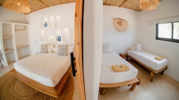 Een kamer met een groot bed, een kleiner bed, een raam en een inbouwkast.