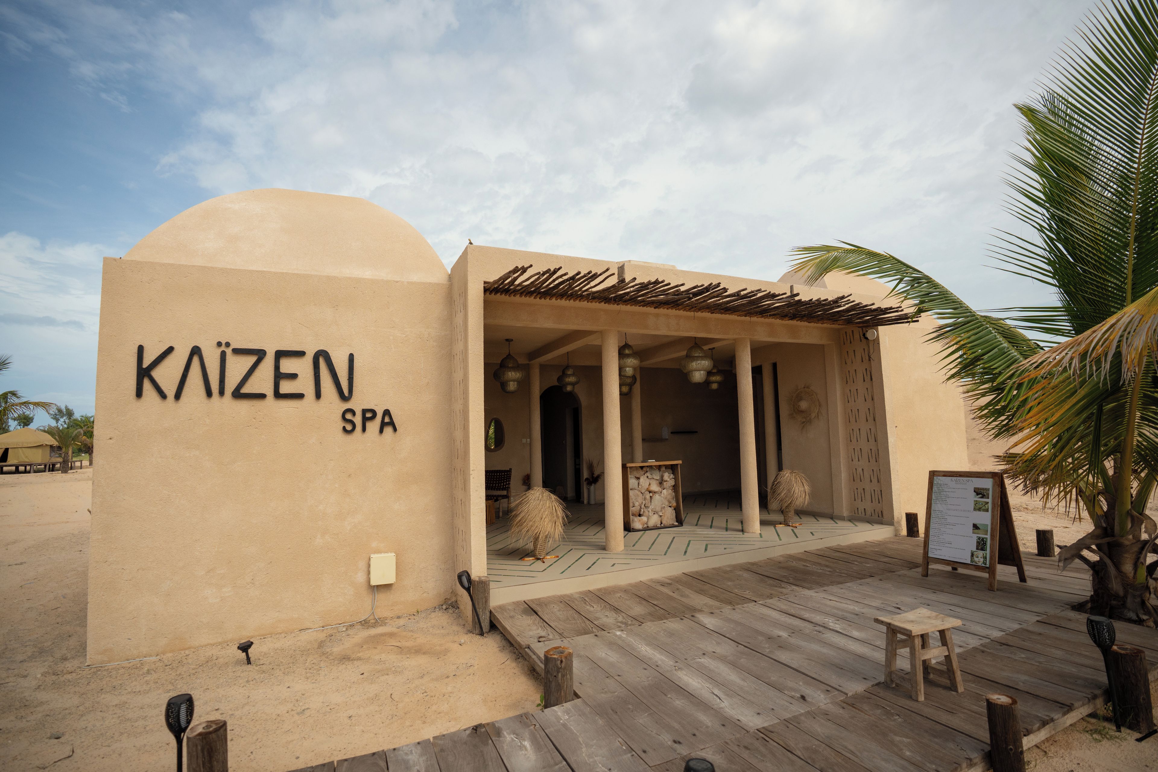 A spa named 'KAIZEN SPA' with a wooden deck and a palm tree.