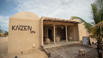 A spa named 'KAIZEN SPA' with a wooden deck and a palm tree.