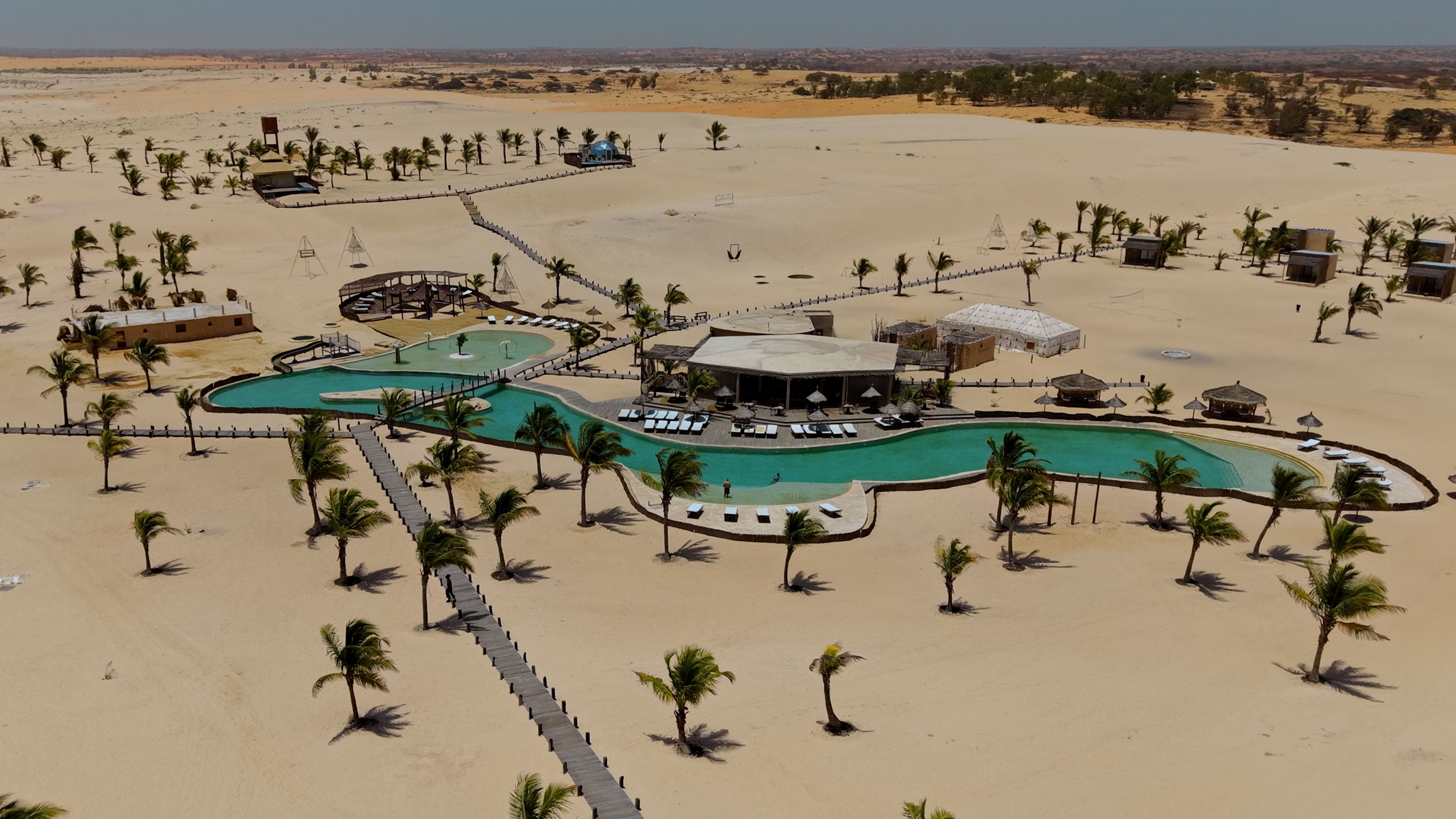 A resort with a pool, palm trees, and desert landscape.