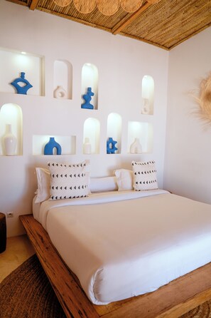 Un dormitorio con cama, almohadas y luminarias fijadas a la pared.