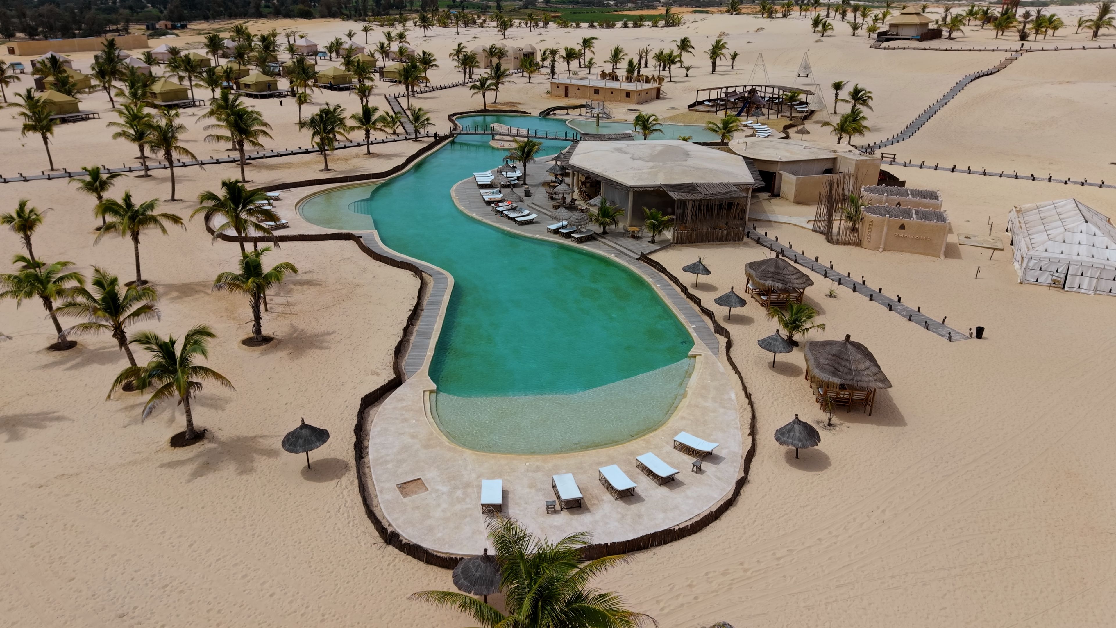 Un resort con piscina, playa y palmeras.