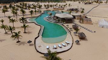 Un resort con piscina, playa y palmeras.