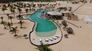 Um resort com piscina, praia e palmeiras.