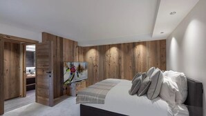 Ein modernes Schlafzimmer mit einem großen Bett, Holzwandverkleidung und einem Gemälde an der Wand.