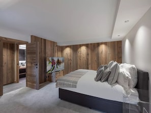 Ein modernes Schlafzimmer mit einem großen Bett, Holzwandverkleidung und einem Gemälde an der Wand.