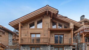 Eine zweigeschossige Holzhütte mit Steinverzierungen, Balkonen und großen Fenstern.